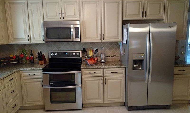 Modern kitchen with cream cabinets, stainless steel appliances, and beige backsplash