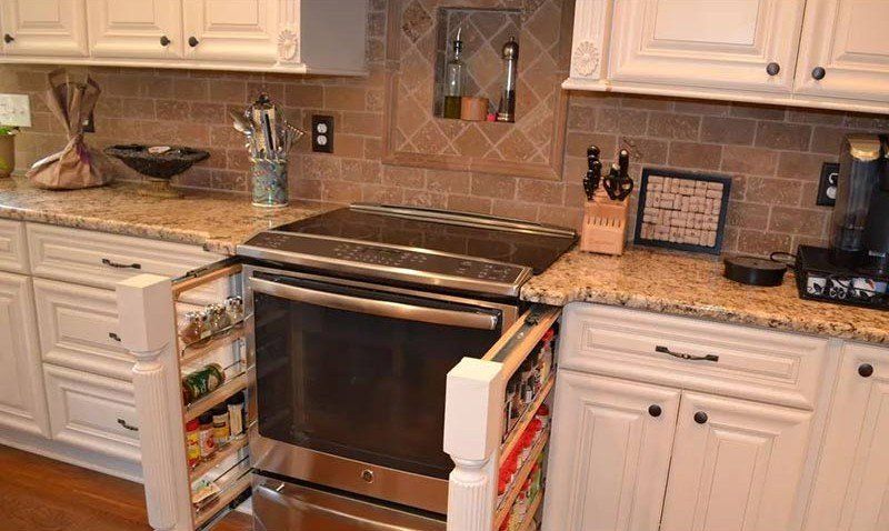 Kitchen with white cabinets, granite counters, and a stainless steel stove centered beneath a tiled backsplash.