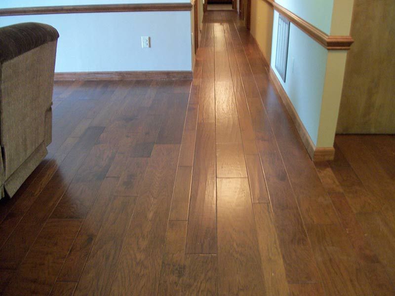 Empty hallway with brown hardwood floors and white walls, lit by daylight.