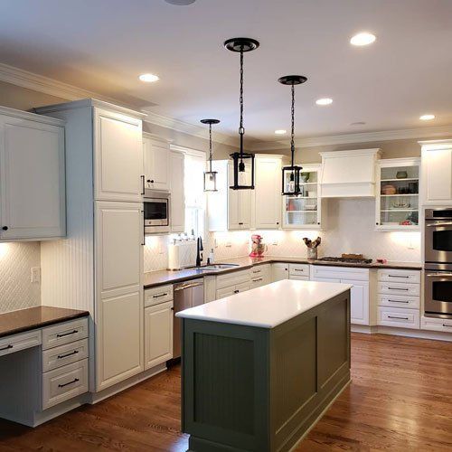 Modern white kitchen with green island, stainless appliances, and pendant lights