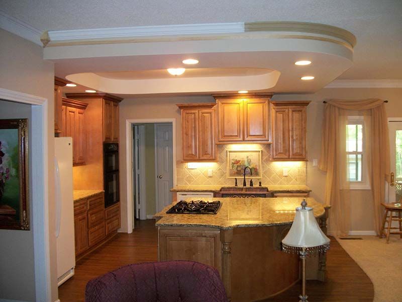 Modern kitchen with wood cabinets, granite island, recessed lights, and a curtained doorway
