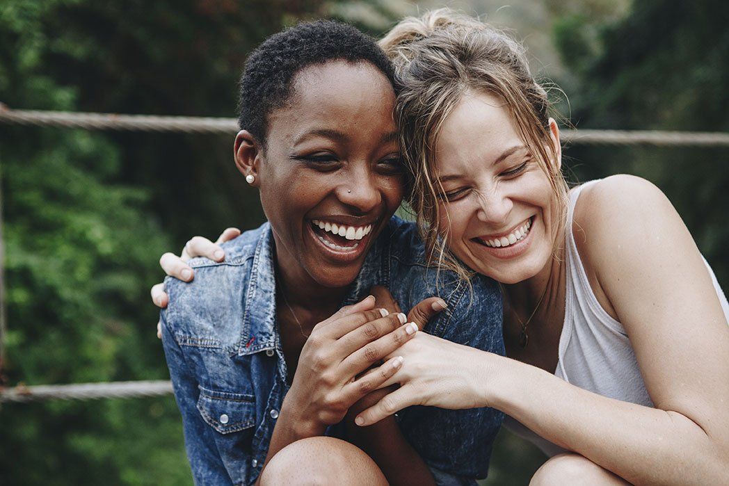 Two women are sitting next to each other and smiling.