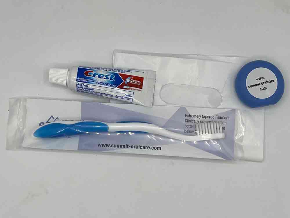 A tube of toothpaste , a toothbrush , and a toothpick are in a plastic bag.