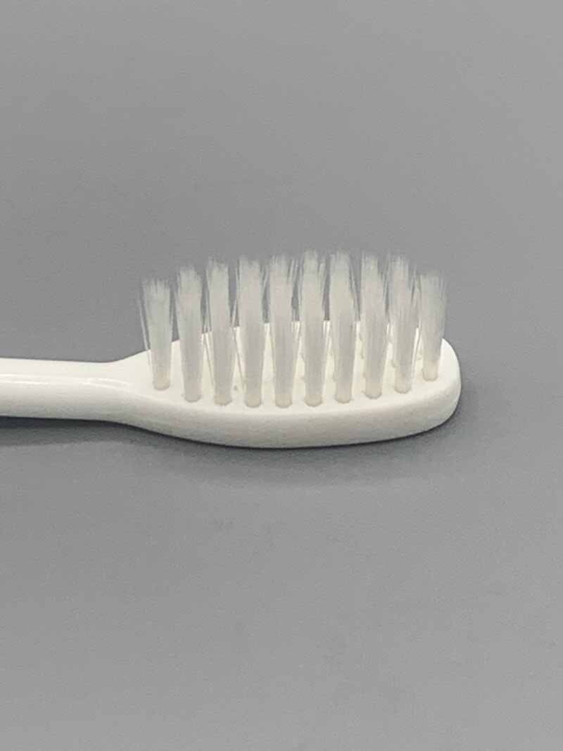 A close up of a white toothbrush on a gray surface.