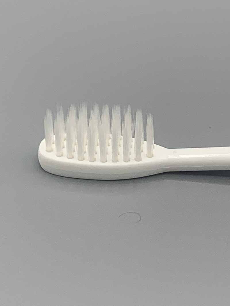 A close up of a white toothbrush on a gray surface.