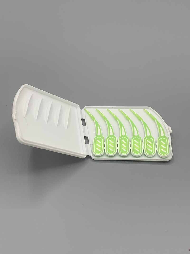 A white box filled with green toothpicks on a gray surface.