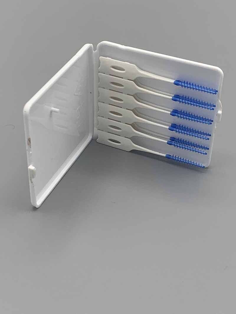 A white case filled with toothpicks on a gray surface.