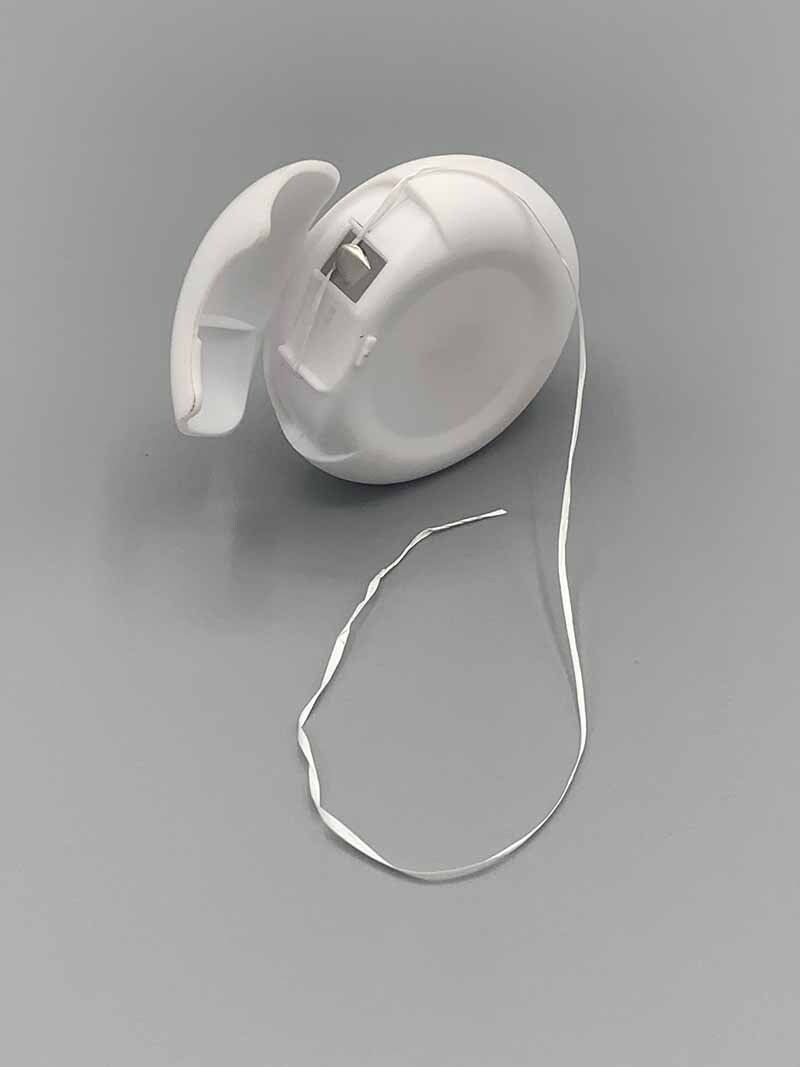 A roll of dental floss is sitting on a gray surface.