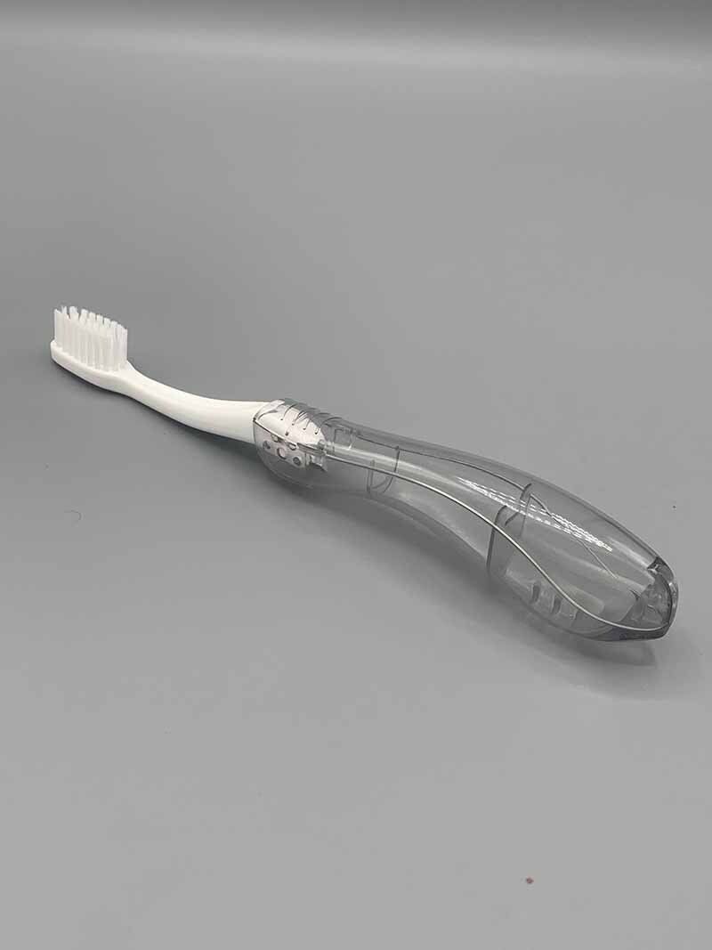 A toothbrush with a clear handle is sitting on a gray surface.