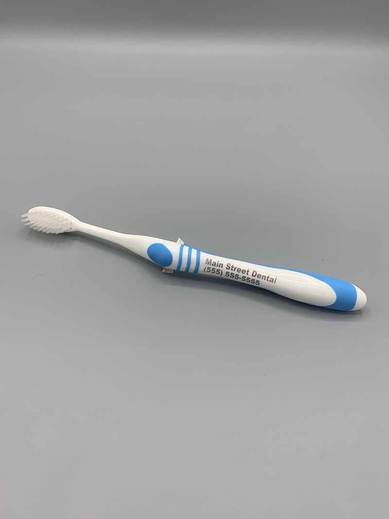 A white and blue toothbrush is sitting on a gray surface.