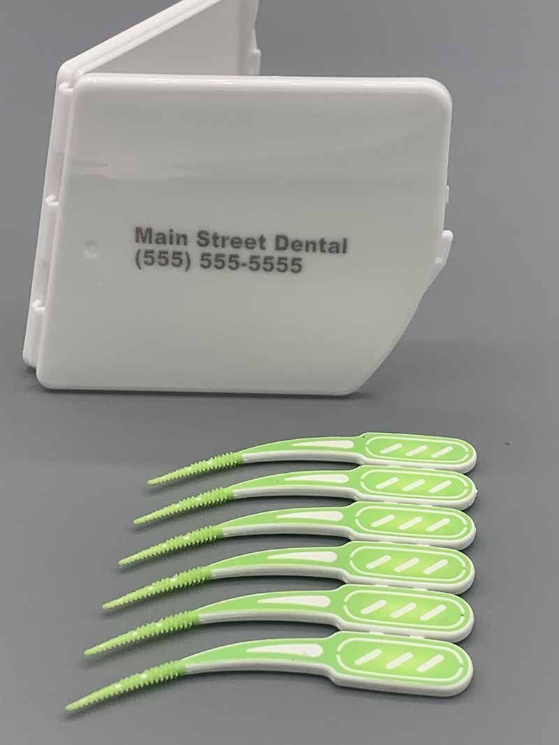 A row of green interdental brushes next to a box that says main street dental
