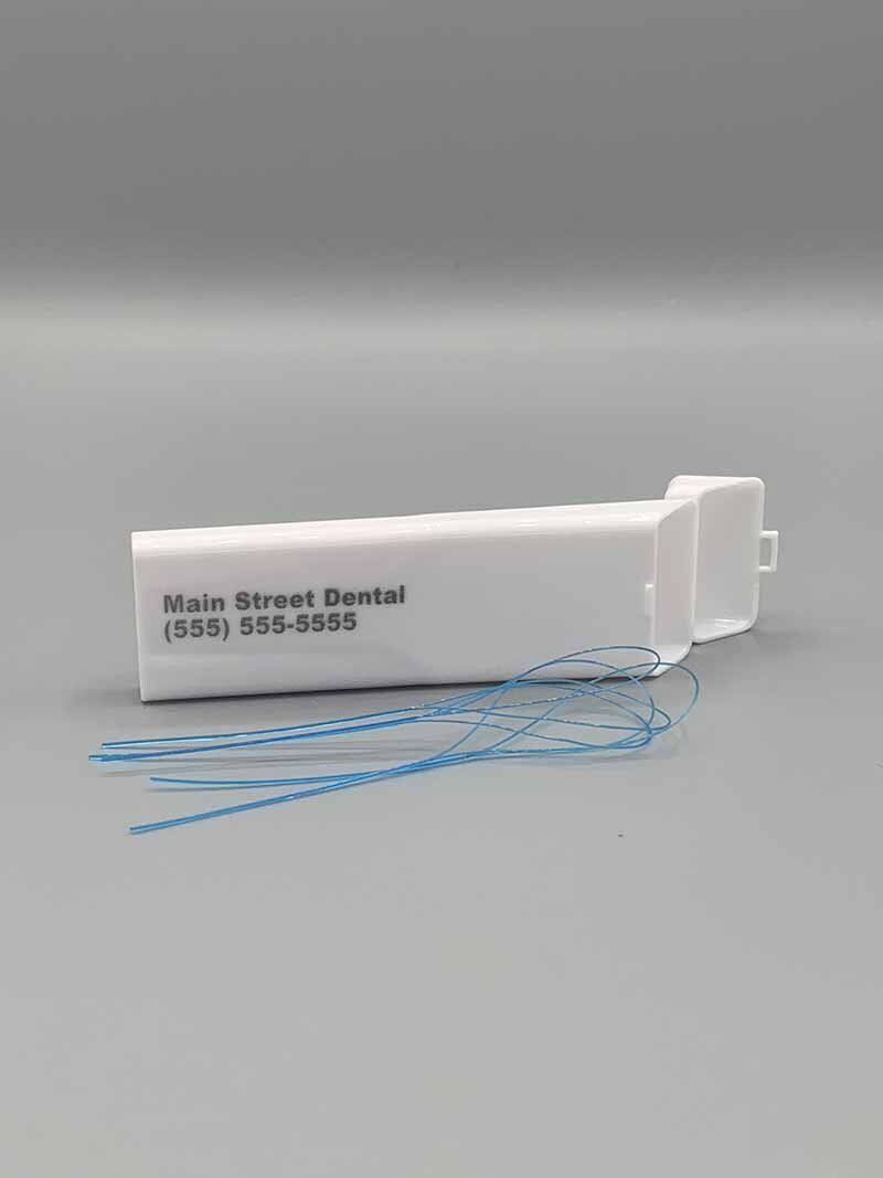 A white box filled with blue floss is sitting on a gray surface.