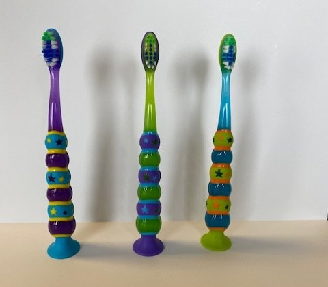 Four colorful toothbrushes are lined up on a table