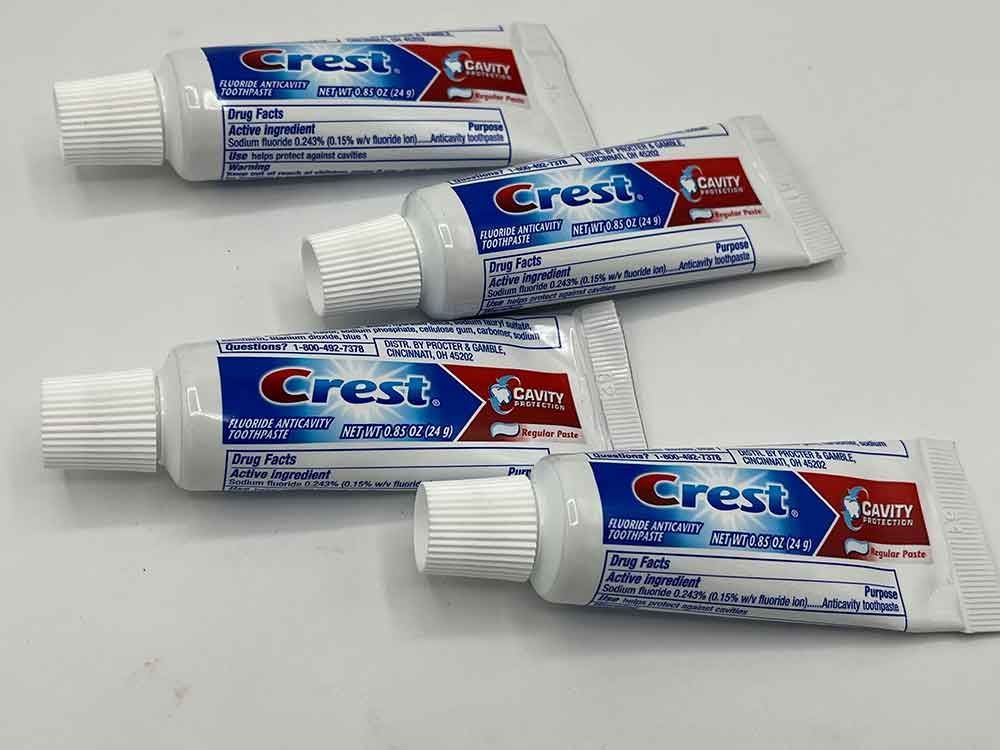 Four tubes of crest toothpaste are sitting on a table.