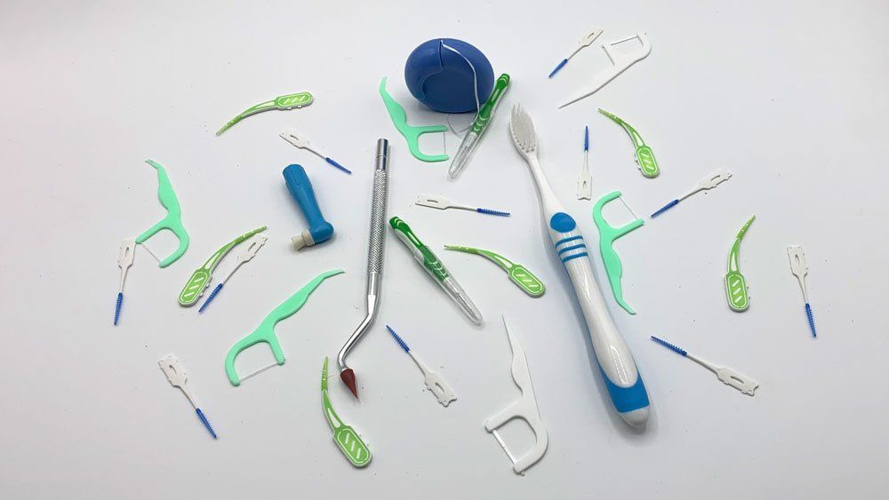 A bunch of toothbrushes and dental floss on a white surface