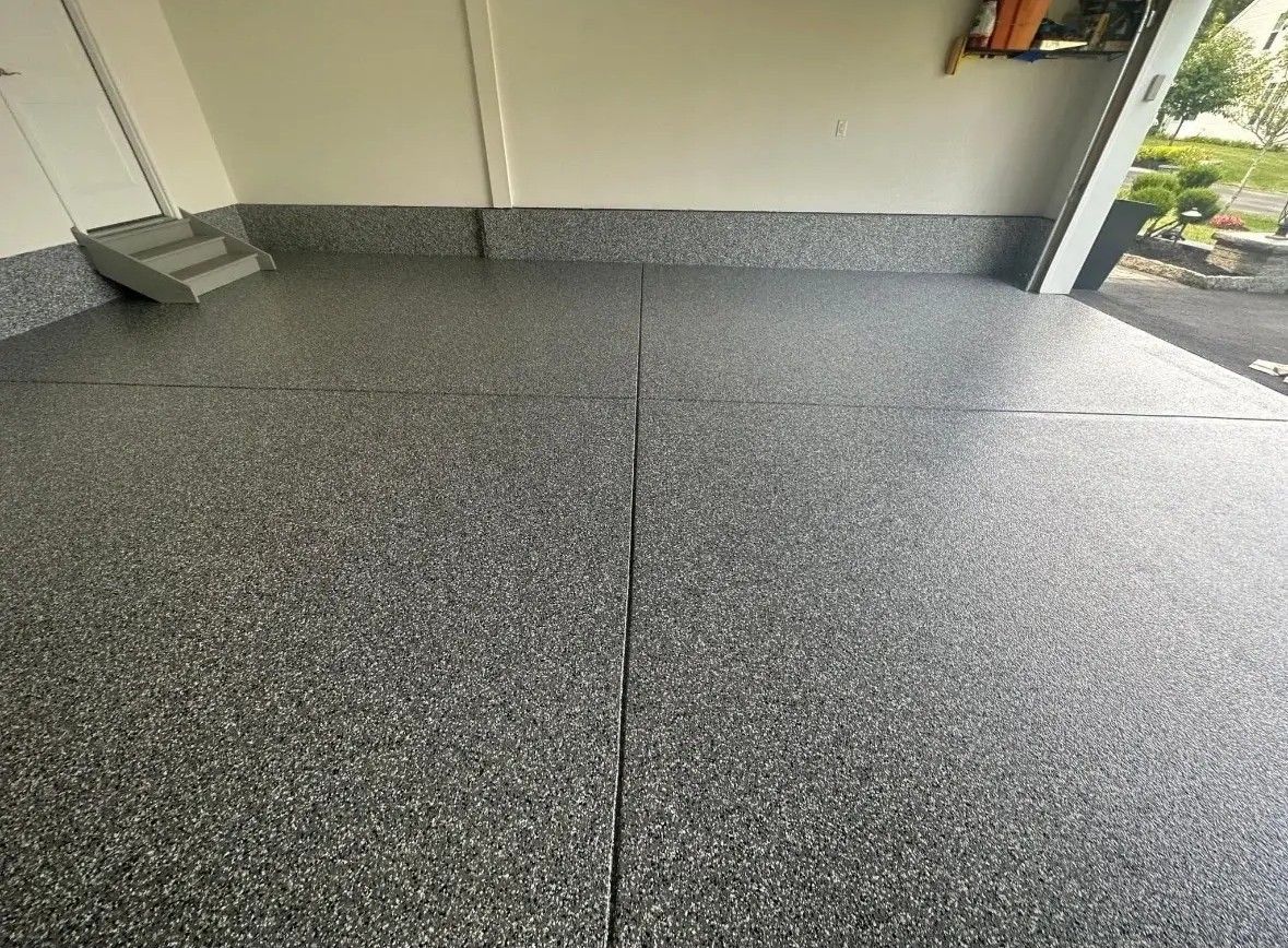 Textured gray concrete floor beside a garage opening and wall