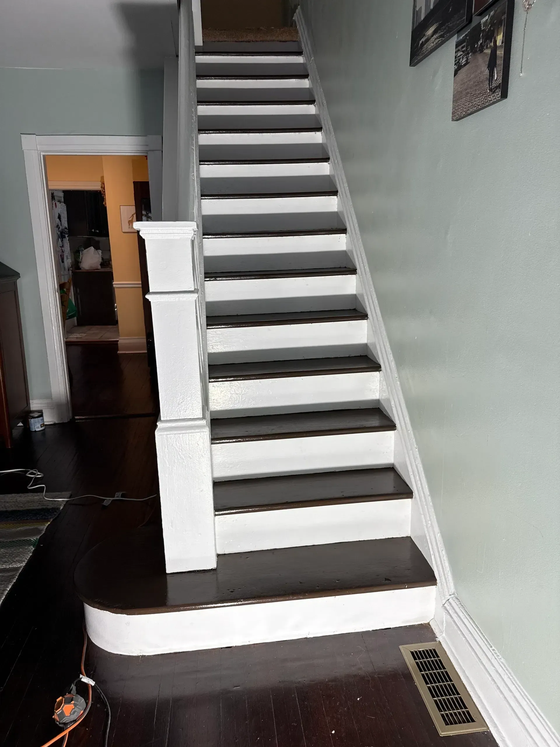 Interior staircase with dark treads and white risers in a narrow hallway.