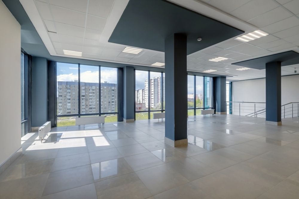 Empty modern office interior with large windows and city view, gray floor, and black columns