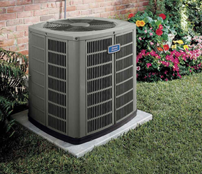 Outdoor air conditioning unit beside a brick wall and flower garden
