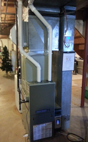Furnace and ductwork installed in a basement utility room, beside a concrete pillar.