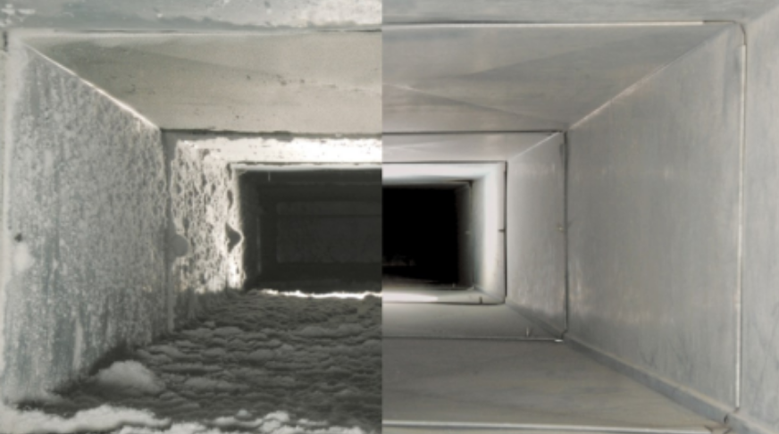 Dust-covered rectangular air duct interior with a dark opening and debris on the bottom
