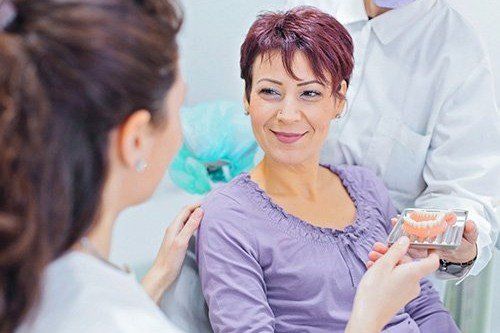 a woman is sitting in a dental chair talking to a dentist .
