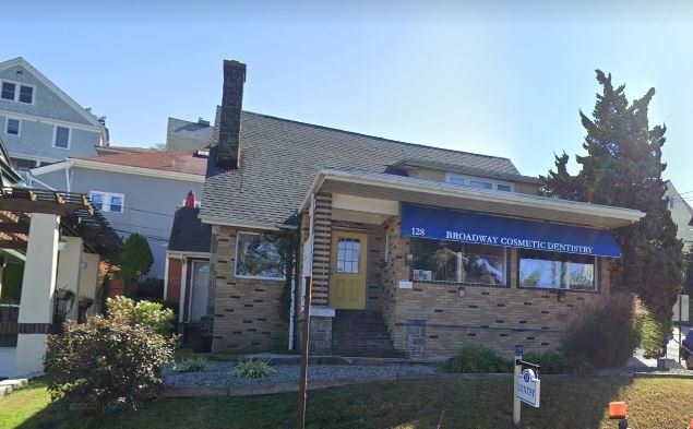 A large brick house with a yellow door and a blue awning.