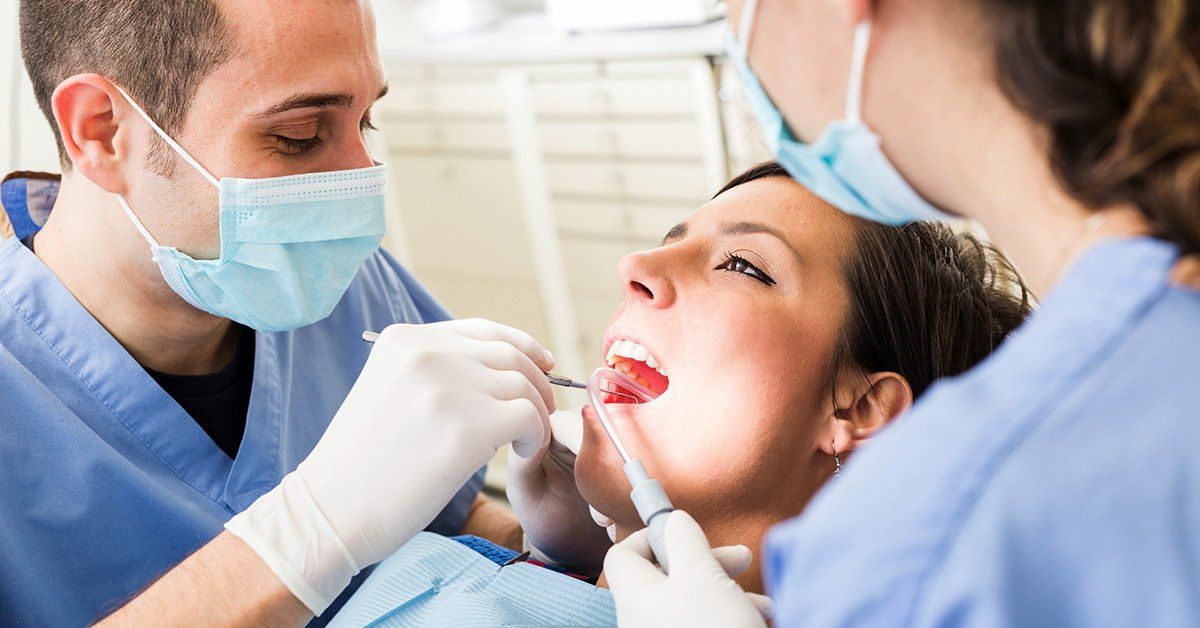 a woman is getting her teeth examined by two dentists