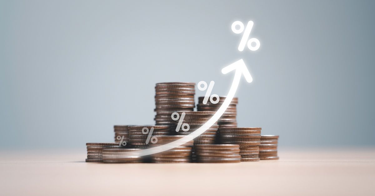 Several stacks of coins on a light surface against a gray-blue background, with a graph line moving
