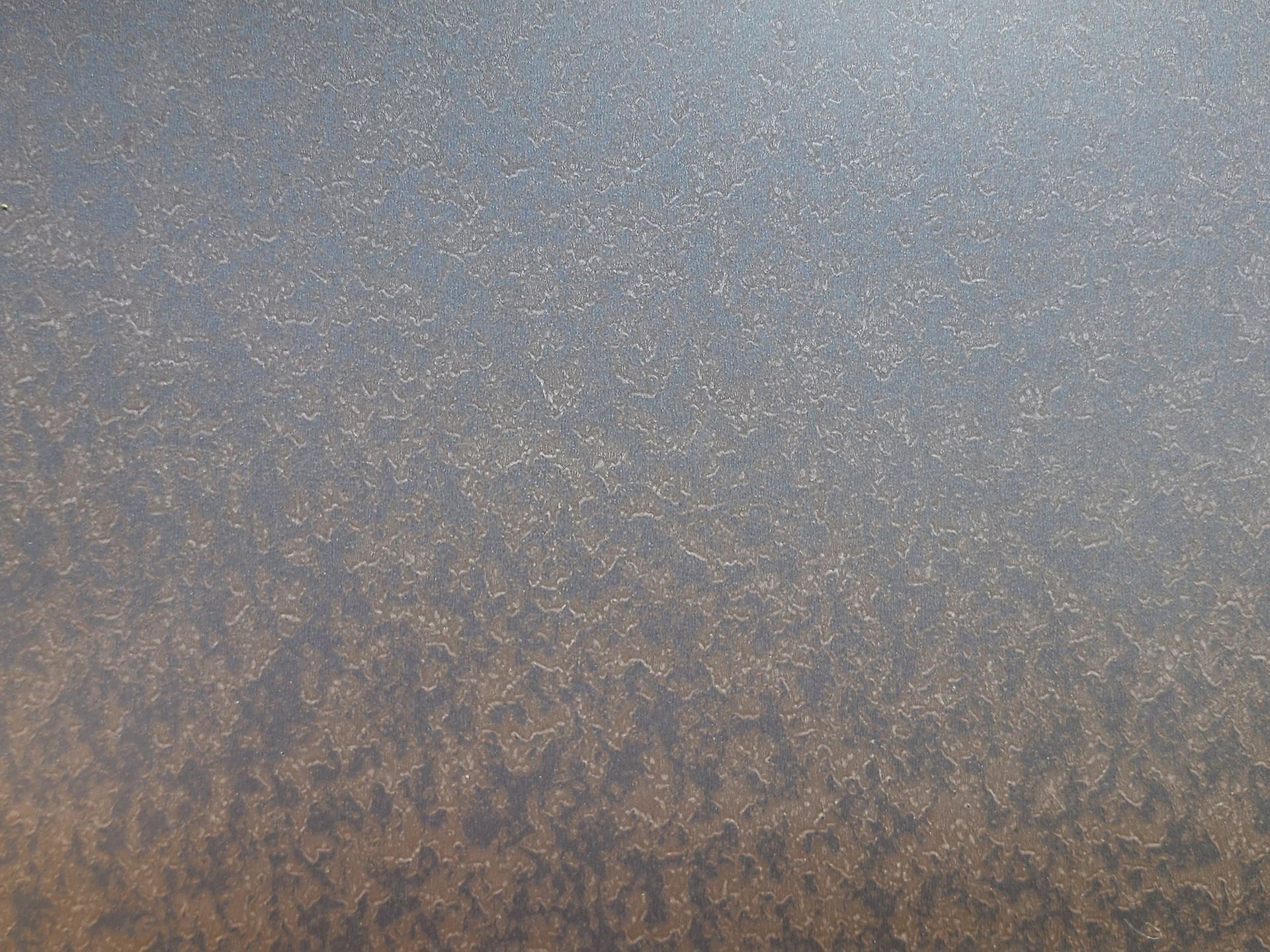 A close-up of a textured, dark surface with small, glittering gold particles.