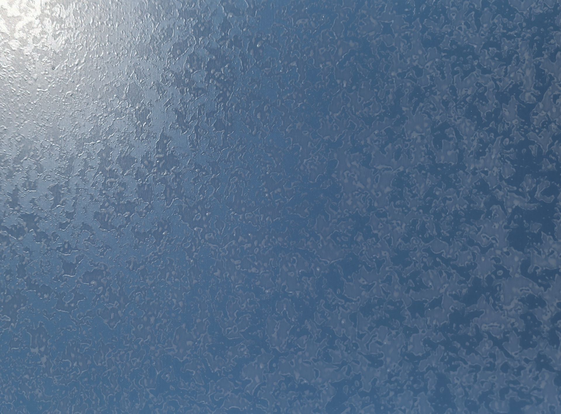 Frosted blue surface, textured with light and shadow, possibly a frozen window.