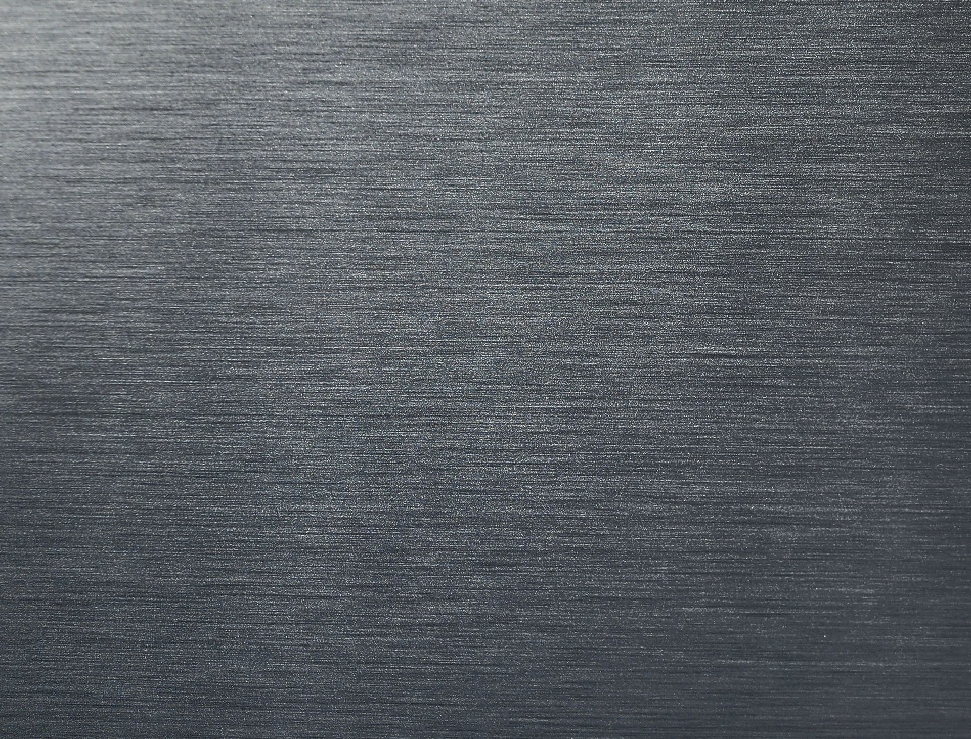 Brushed, textured metal surface in shades of gray, reflecting light horizontally.