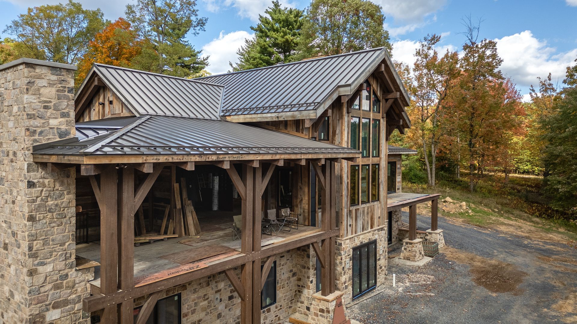 Rustic cabin with stone and wood exterior, surrounded by autumn trees.