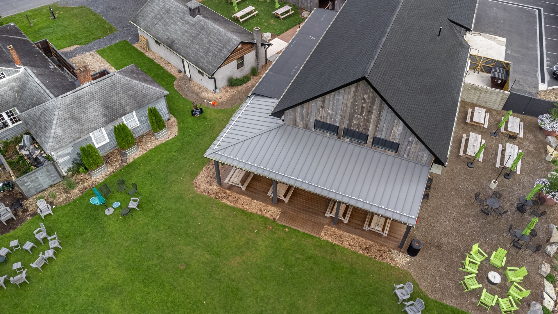 Aerial view of a brewery with a large wooden building, green lawn, and outdoor seating areas.