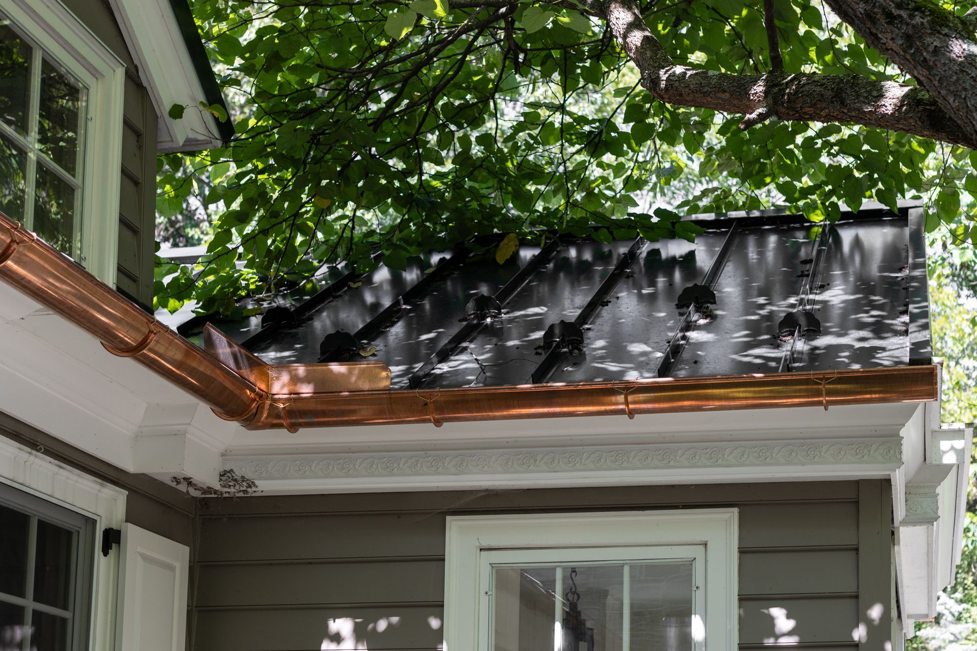 Copper gutters and trim on a house with a tree overhead.