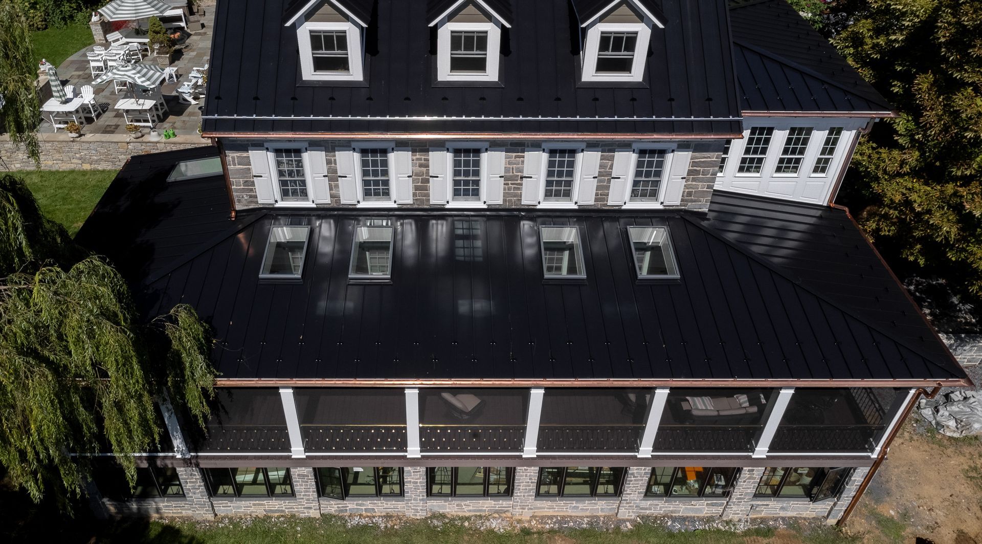 Overhead view of a dark roofed building with multiple windows and a screened-in porch.