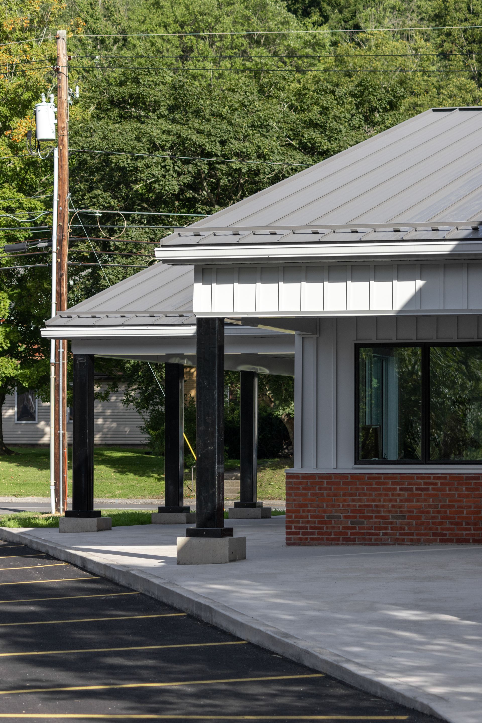 Modern building with black pillars and a metal roof; brick and gray siding.