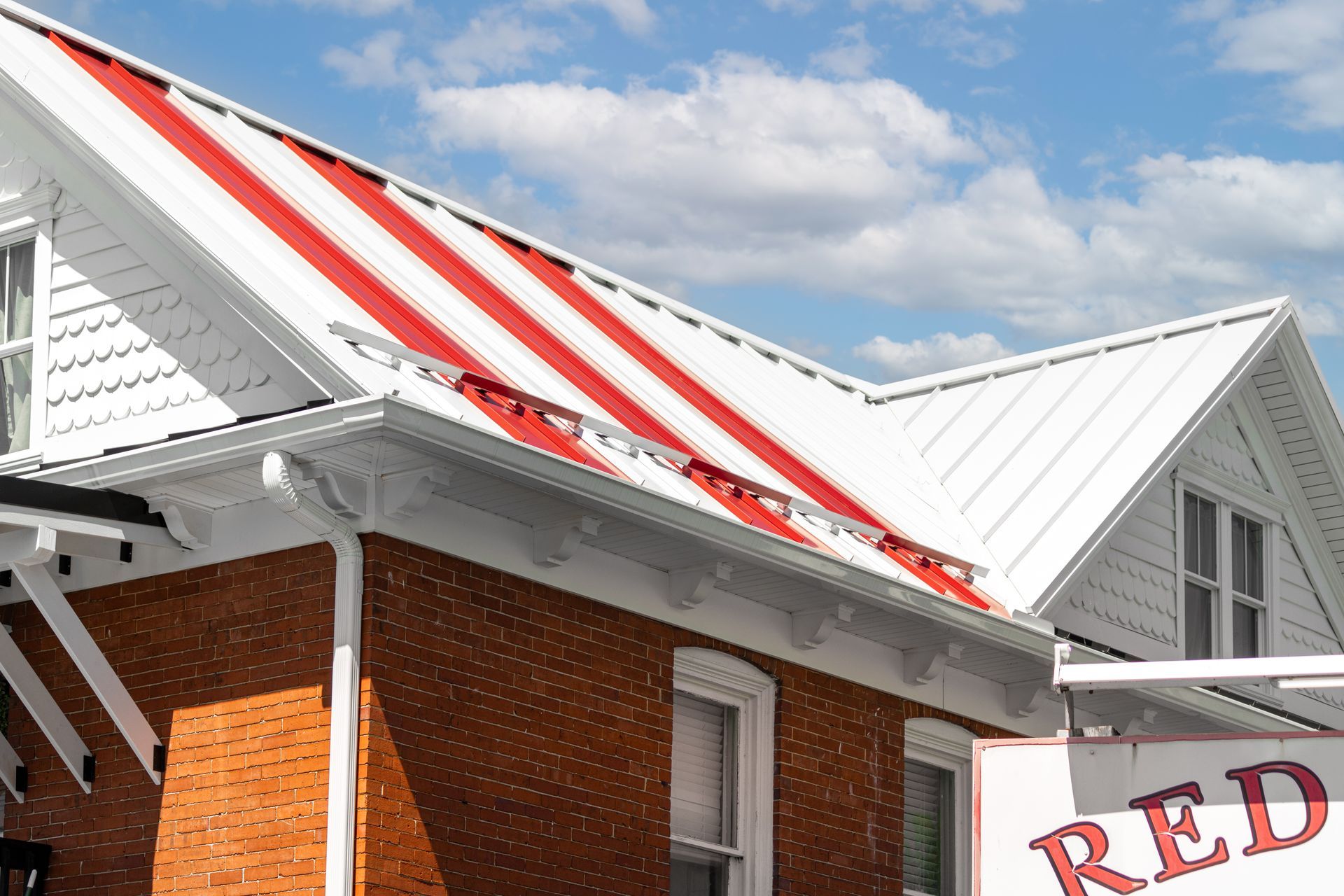 Red and white striped roof on a brick building against a partly cloudy sky.