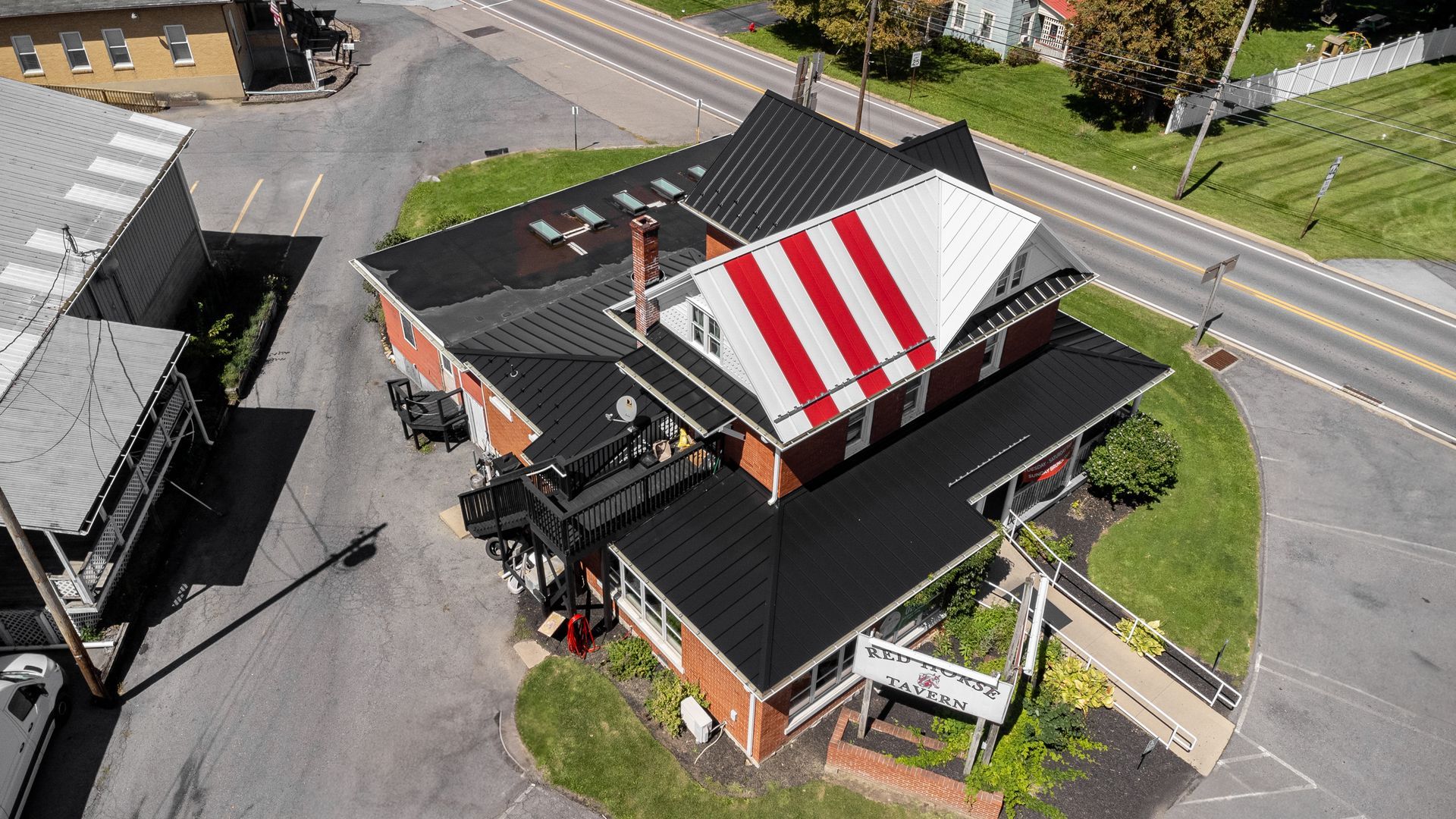 Aerial view of a brick building with a black roof and a striped red and white gable.