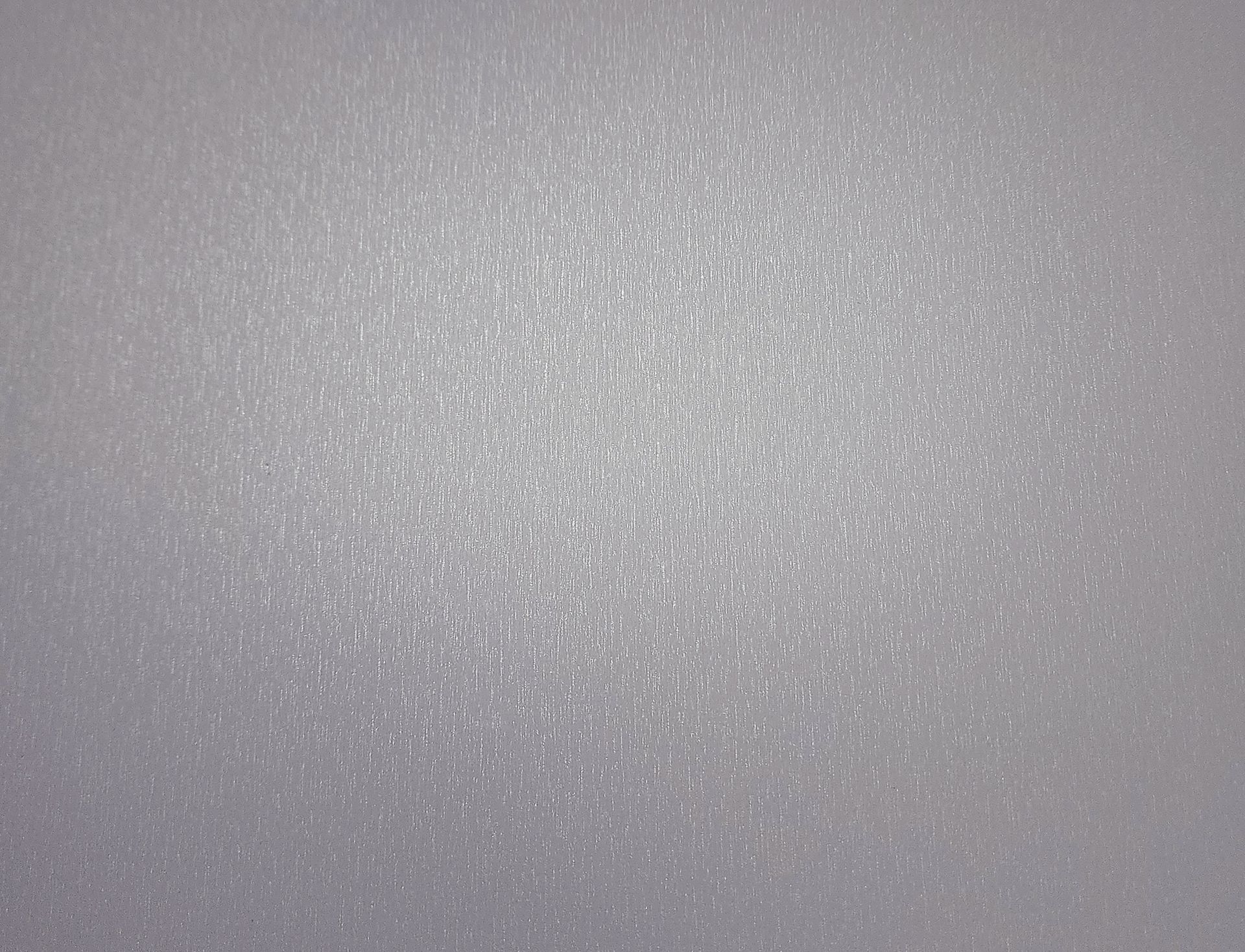 A gray, speckled surface with brighter highlights at the center, possibly a textured material.