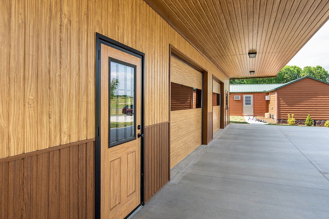Building with brown and tan siding, a light brown door, and a concrete walkway.