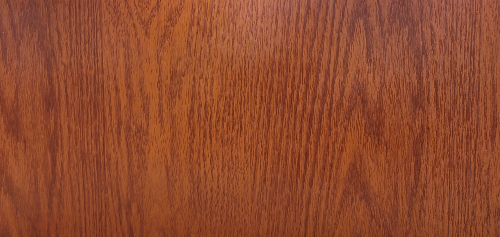 Close-up of a wooden surface with a reddish-brown color and vertical grain patterns.