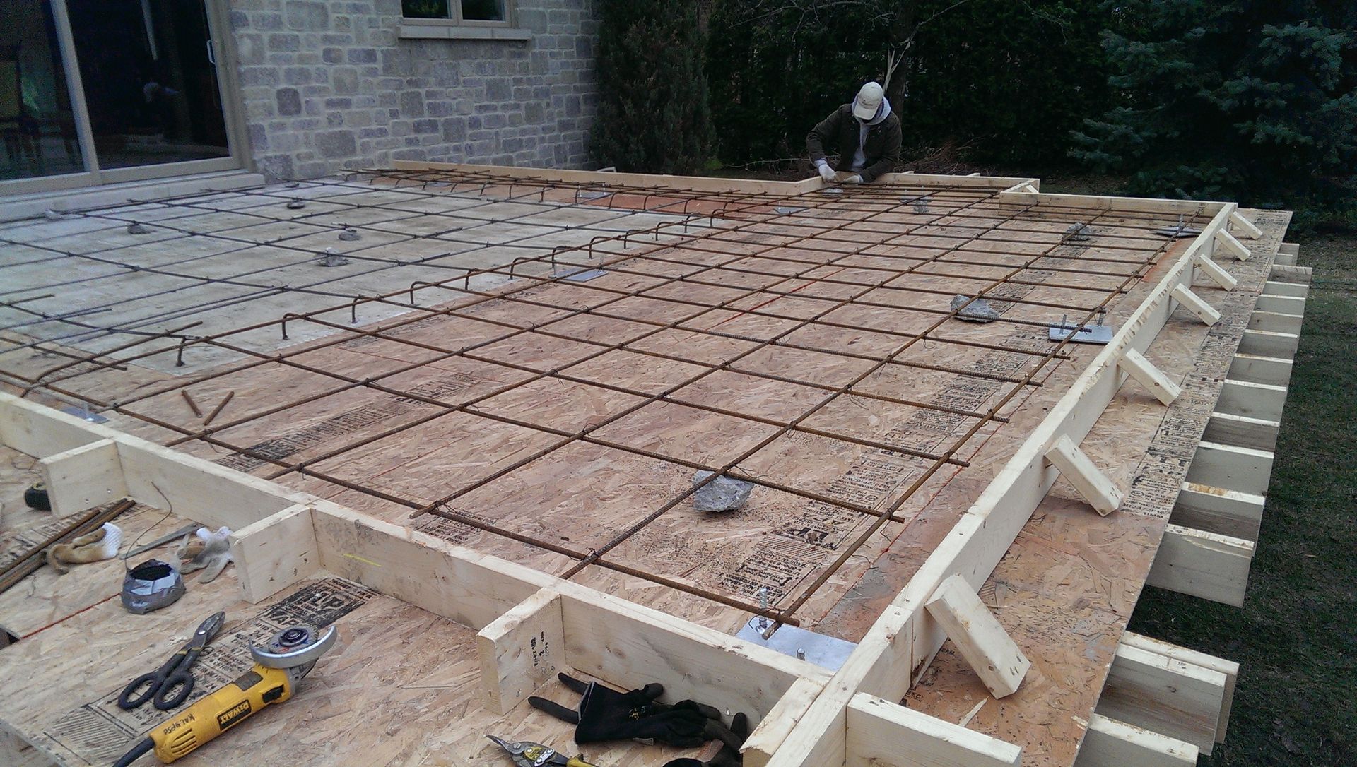 Construction d'une fondation en dalle de béton avec treillis d'armature et ossature en bois à l'extérieur.