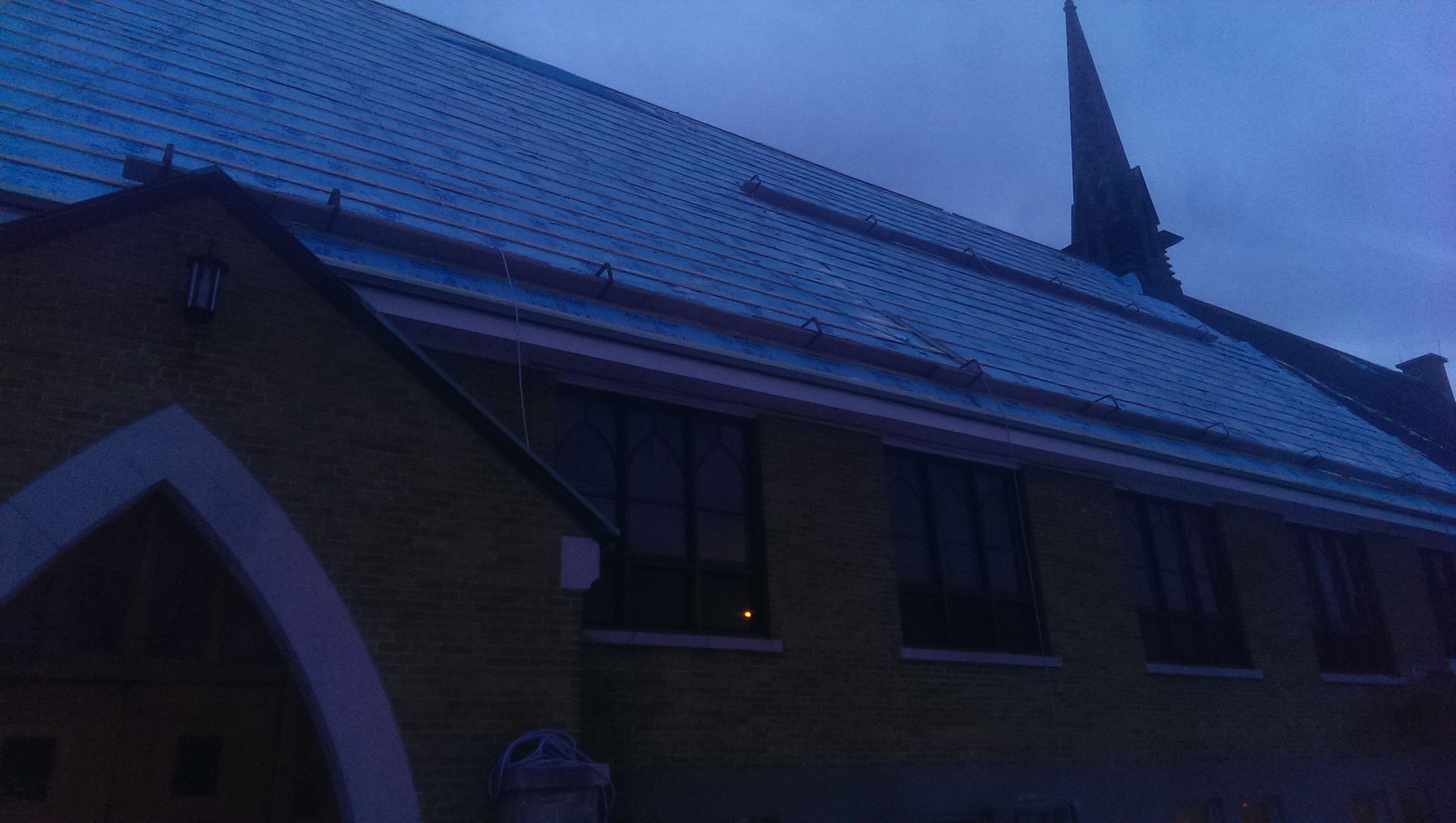 Église avec un ciel bleu foncé, un clocher et une façade en briques jaunes.