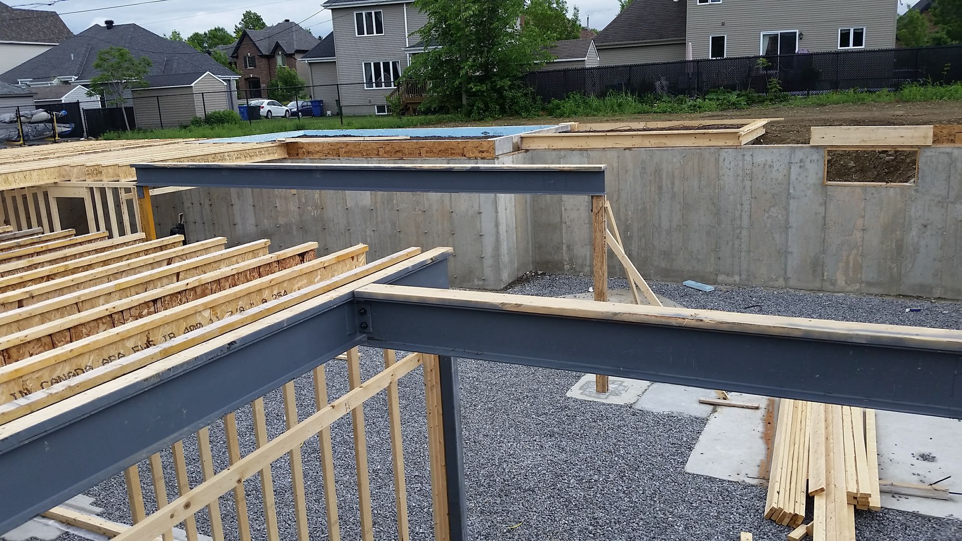 Chantier de construction, fondations, charpente en bois apparente et poutres en acier.
