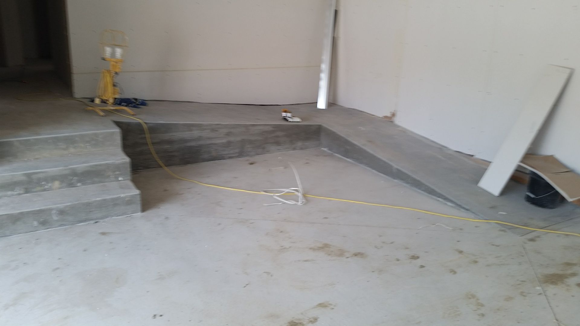 Chantier de construction avec escaliers en béton, rampe et câbles électriques apparents.
