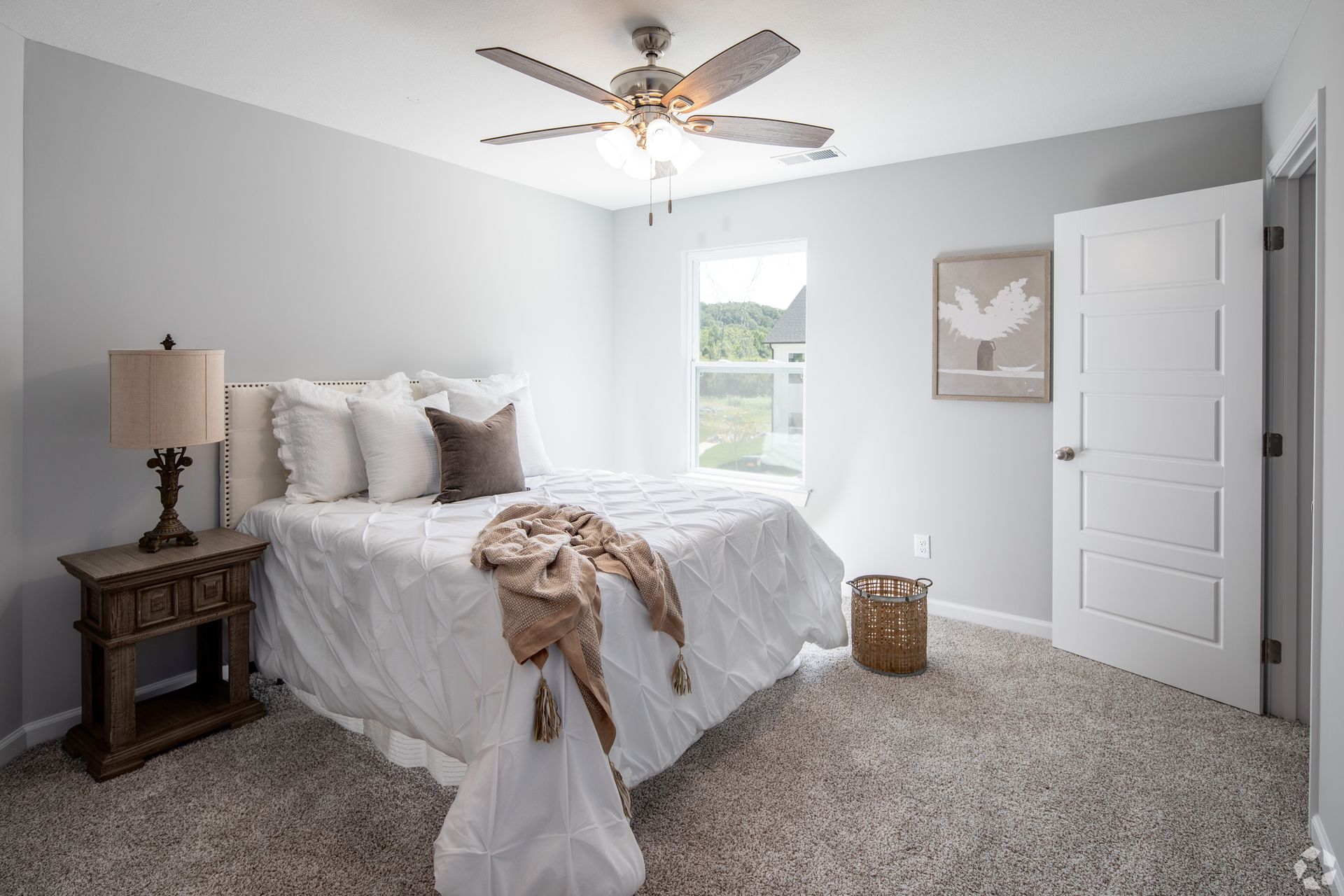 Bedroom with a bed, nightstand, ceiling fan, carpet, door, and artwork.