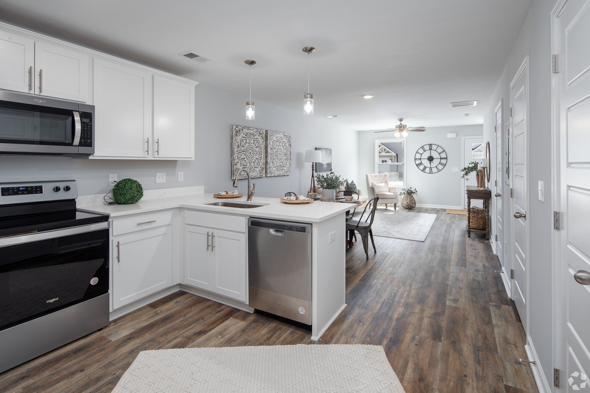 Modern kitchen with stainless steel appliances, white cabinets, and open layout to dining and living area.