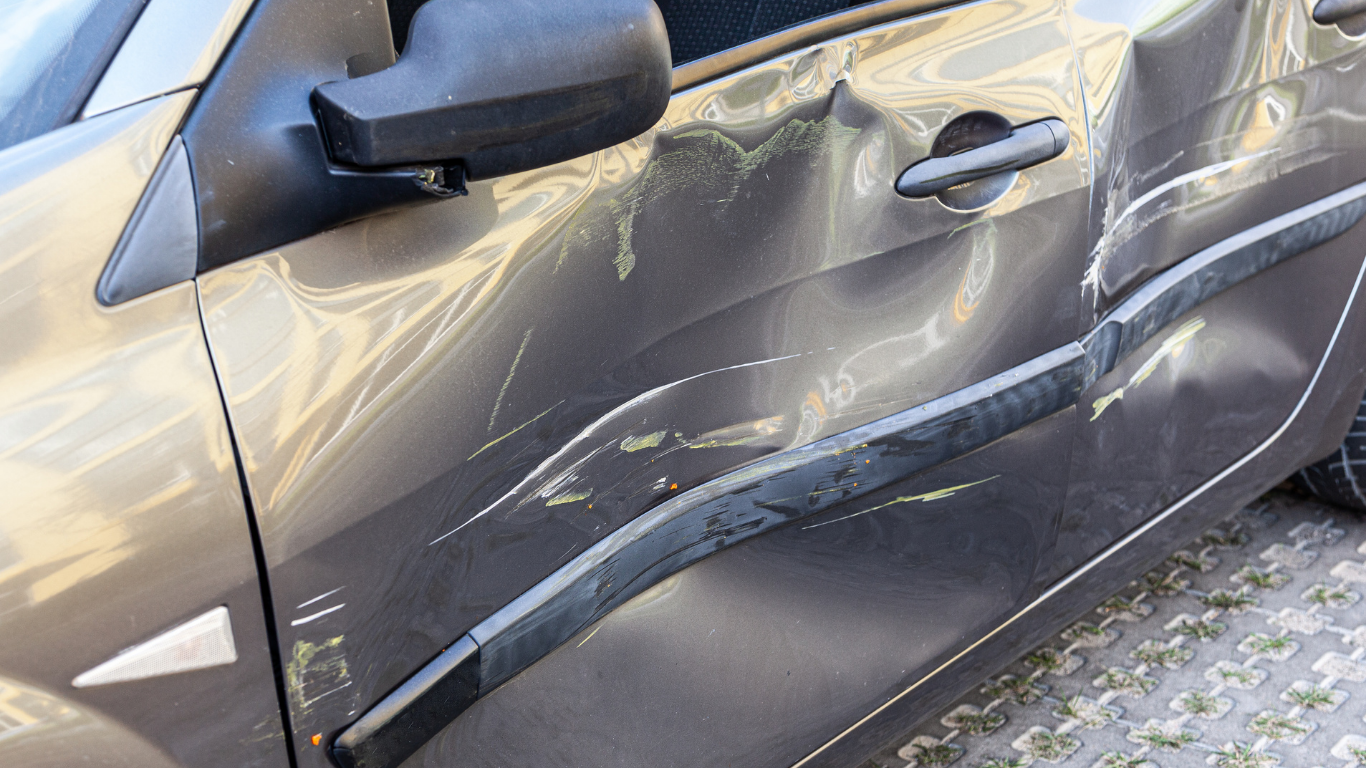 Windshield wipers on a car, clearing the glass. Bright sunlight is visible through the windshield.