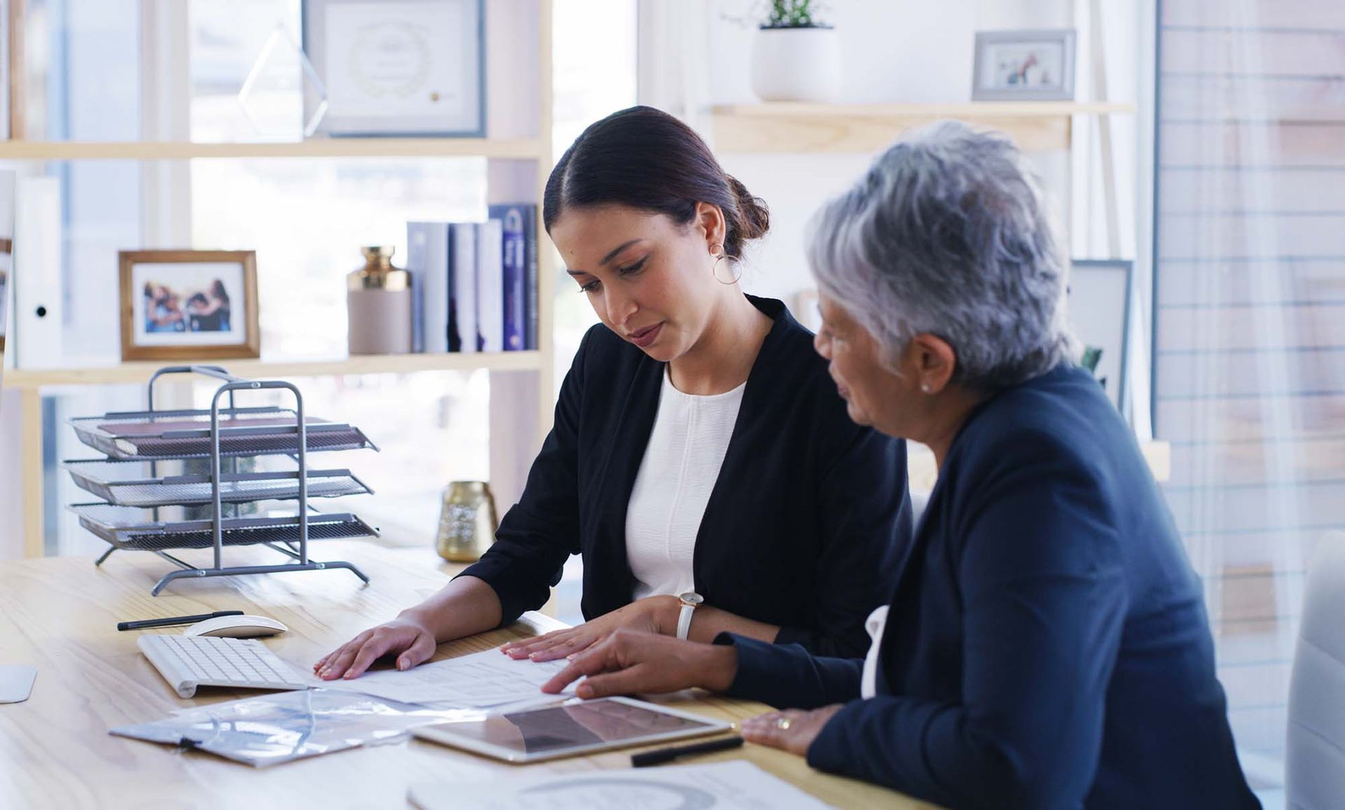 Two coworkers reviewing documents together at a desk in a bright office